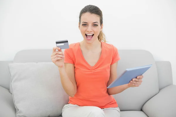 Cheering brunette woman showing her credit card holding her table — Stock Photo, Image