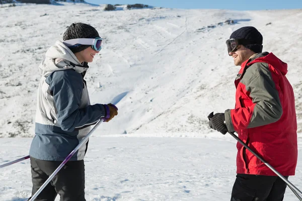 Vista laterale di una coppia sorridente con bastoni da sci sulla neve — Foto Stock