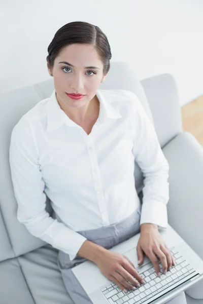 Goed geklede jonge vrouw met laptop op sofa — Stockfoto