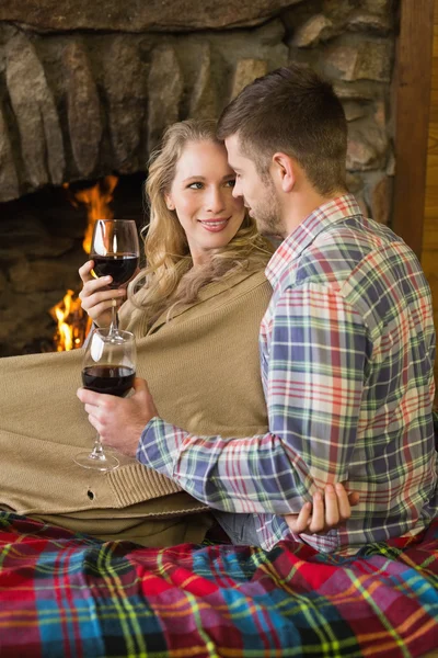 Pareja romántica con gafas de vino frente a la chimenea encendida — Foto de Stock