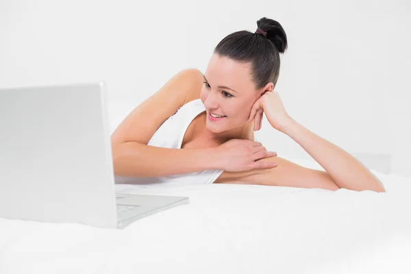 随便面带笑容的女人在床上使用笔记本电脑 — 图库照片