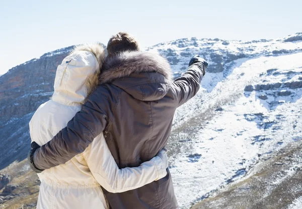 Couple in fur hood jackets looking at snowed mountain range — Stock Photo, Image
