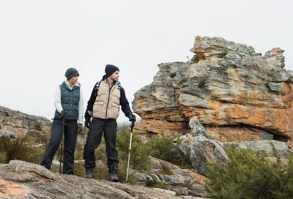 Koppel op rotsachtige landschap met trekking Polen tegen hemel — Stockfoto