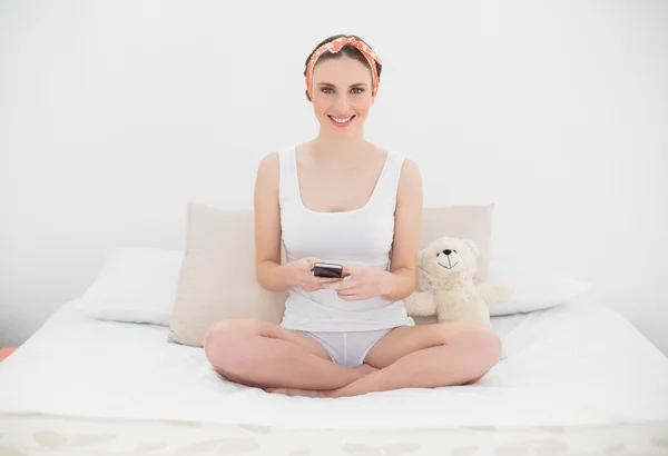 Mujer joven sonriente sosteniendo su teléfono inteligente — Foto de Stock