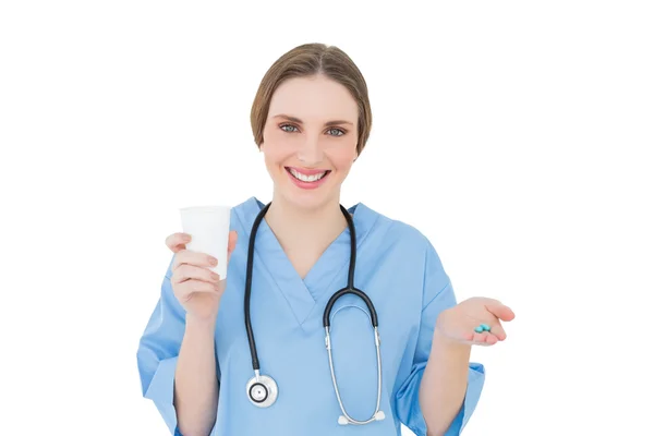 Female doctor holding a plastic cup and blue pills — Stock Photo, Image