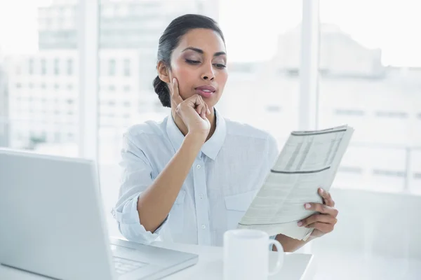 Fokuserade affärskvinna läsa tidningen sitter vid hennes skrivbord — Stockfoto