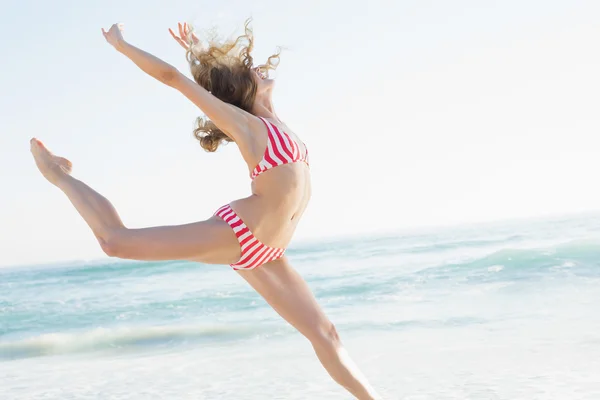 Hermosa mujer joven saltando en la playa — Foto de Stock