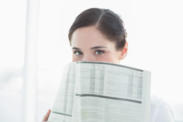 Business woman holding newspaper in front of face — Stock Photo, Image