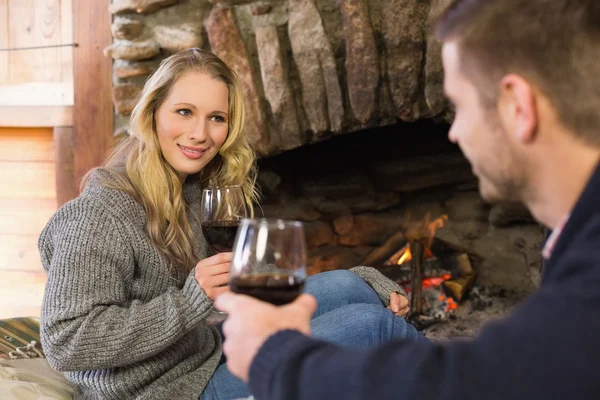 Pareja con gafas de vino en frente de la chimenea encendida — Foto de Stock