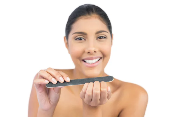 Smiling nude brunette using nail file — Stock Photo, Image