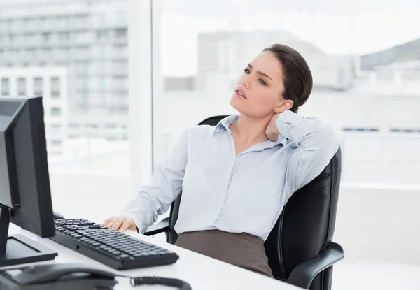 Businesswoman with neck pain sitting at desk Stock Image
