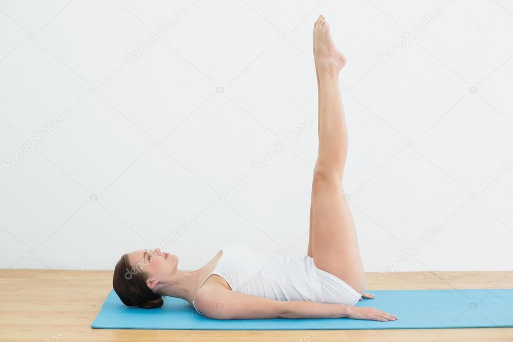 Side view of a woman stretching legs on exercise mat