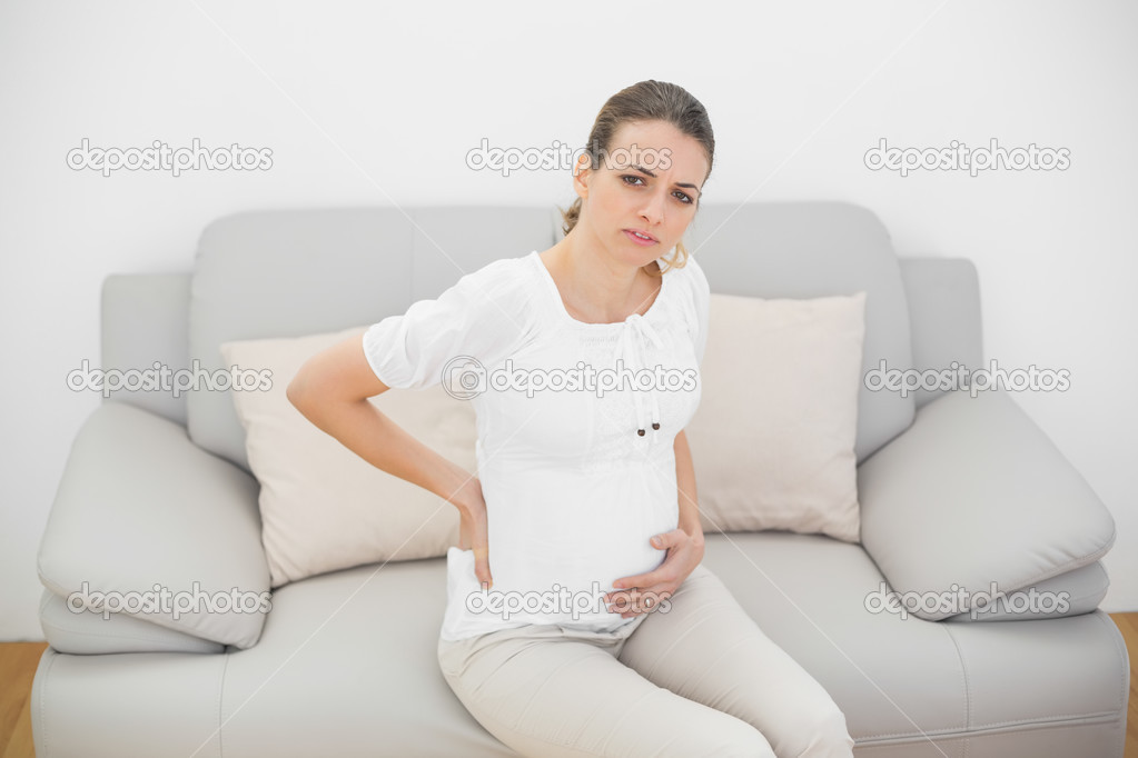 Suffering pregnant woman looking seriously at camera