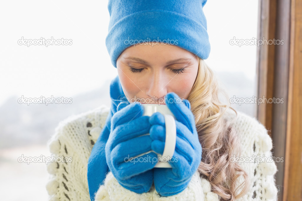 Cute woman drinking coffee in warm clothing