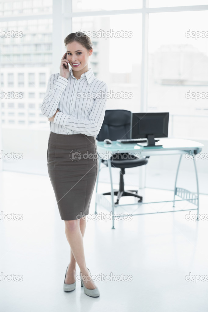 Gleeful calm businesswoman phoning with her smartphone standing
