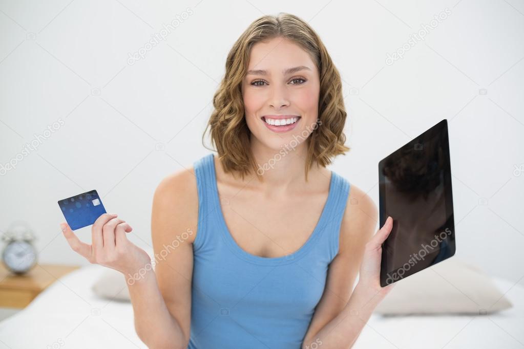 Beautiful calm woman showing her tablet and debit card