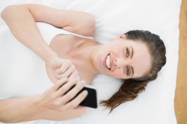 gülümseyen kadın yatakta istimal hareket eden telefon