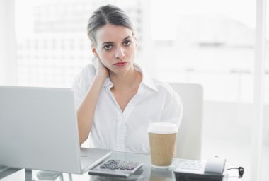Calm serious businesswoman sitting at her desk clipart
