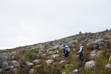 Couple walking through rocky landscape against clear sky clipart