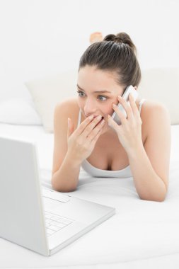 şok kadın yatakta kullanarak cep telefonu ve laptop