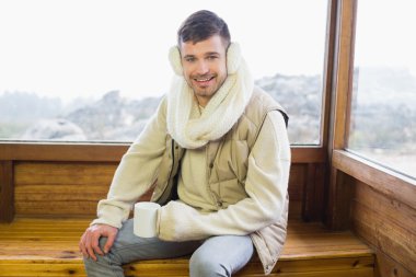 gülümseyen adam pencereye kahve fincanı ile kulaklık takmış