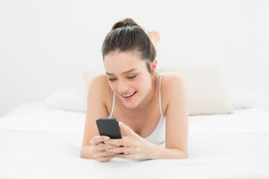 cep telefonu yatakta bakarak mutlu casual kadın