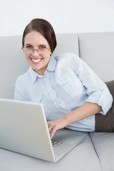 Smartly dressed smiling woman with laptop on sofa — Stock Photo, Image