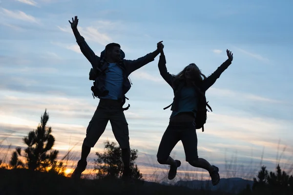 Silhouette couple jumping against the sky — Stock Photo, Image