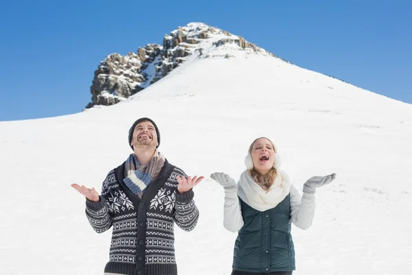 Coppia allegra con le mani aperte guardando verso l'alto di fronte a ciao innevato — Foto Stock