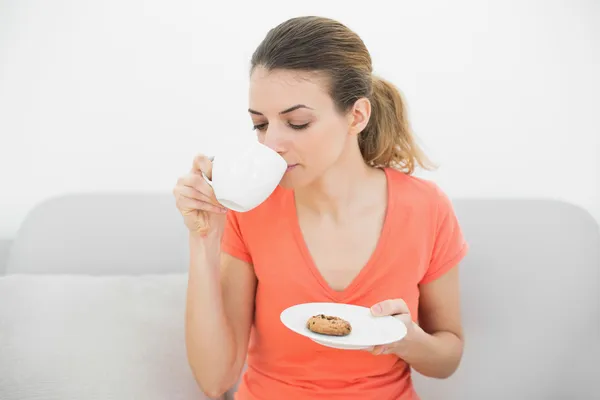 Pacifico encantadora mujer bebiendo de taza sentado relajarse en el sofá —  Fotos de Stock