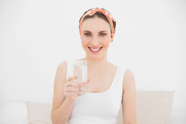 Jeune femme tenant un verre d'eau souriant dans la caméra — Photo