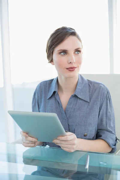 Wunderschöne Geschäftsfrau hält ihr Tablet während sie am Schreibtisch sitzt — Stockfoto