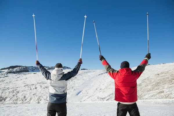Vista posteriore di una coppia che solleva bastoncini da sci sulla neve — Foto Stock