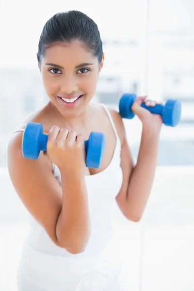 Smiling toned brunette holding dumbbells — Stock Photo, Image