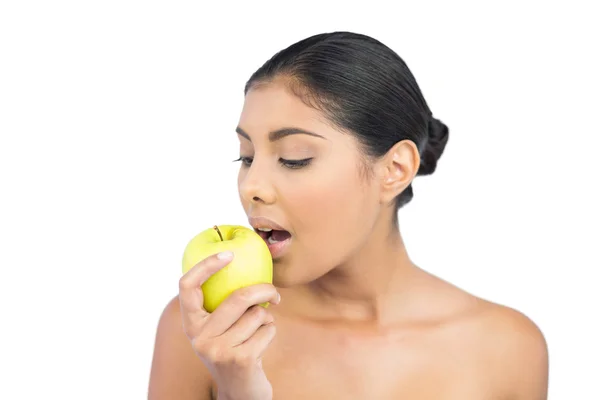 Calm nude brunette eating green apple — Stock Photo, Image