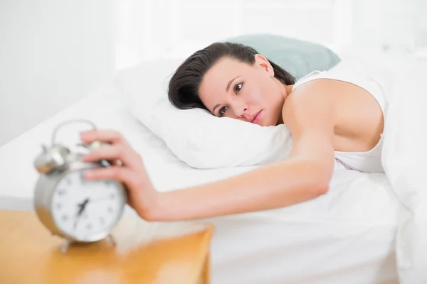 Frau im Bett streckt Hand zum Wecker aus — Stockfoto