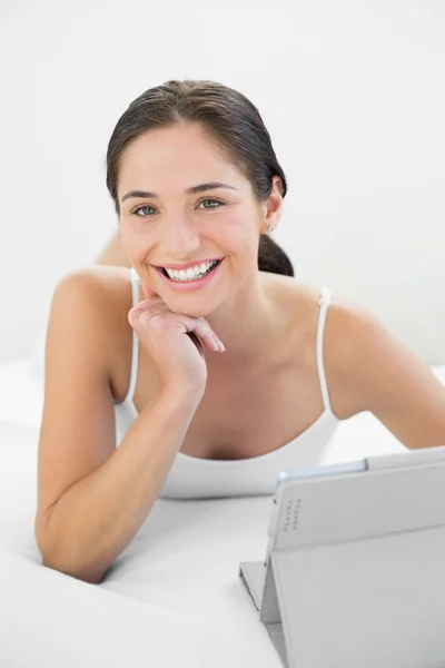 Retrato de una mujer casual sonriente con tablet PC en la cama — Foto de Stock