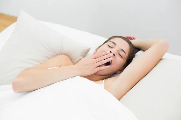 Vrouw geeuwen in bed met de ogen gesloten — Stockfoto