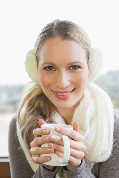 Mujer sonriente usando orejera con café — Foto de Stock