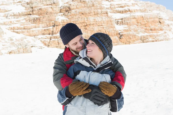 Szczęśliwy człowiek, obejmując kobieta z tyłu na śniegu — Zdjęcie stockowe