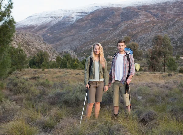 Couple avec sacs à dos et bâtons de trekking contre la montagne — Photo