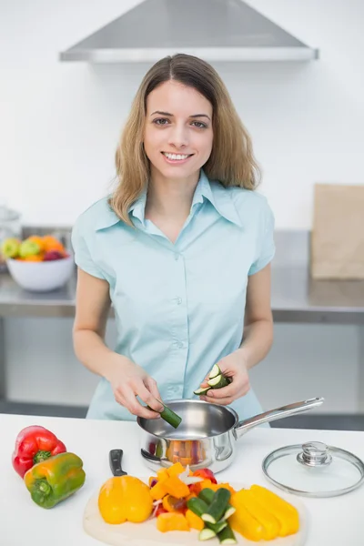 Dulce mujer sonriente cortando verduras de pie en la cocina — Foto de Stock