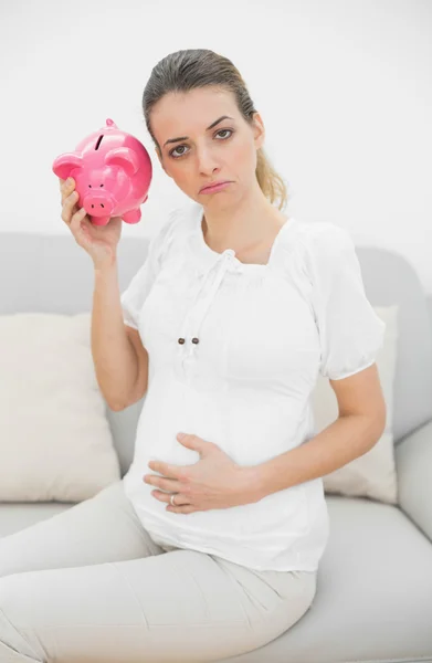 Unhappy pregnant woman shaking a piggy bank — Stock Photo, Image