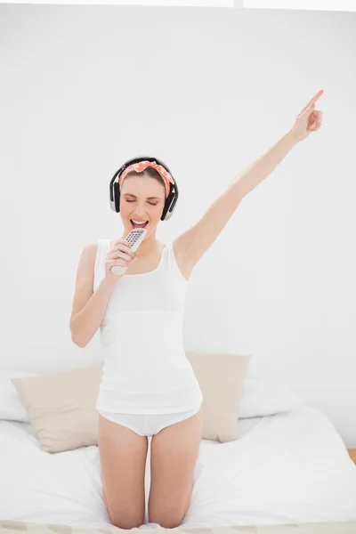 Junge Frau gibt vor zu singen, während sie Musik hört — Stockfoto