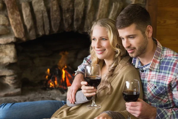 Couple with wineglasses in front of lit fireplace — Stock Photo, Image