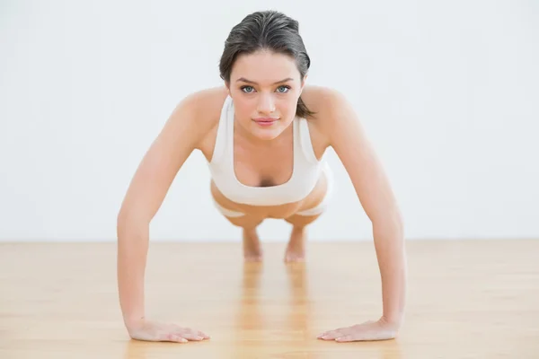 Sportieve jonge vrouw doet push ups in fitness-studio — Stockfoto
