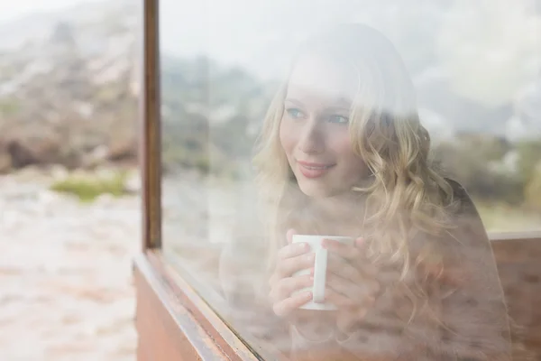 Mulher com xícara de café olhando através da janela da cabine — Fotografia de Stock