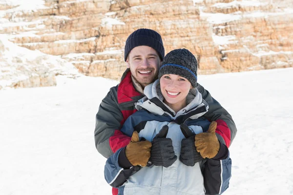 Feliz pareja amorosa gestos pulgares hacia arriba en la nieve —  Fotos de Stock