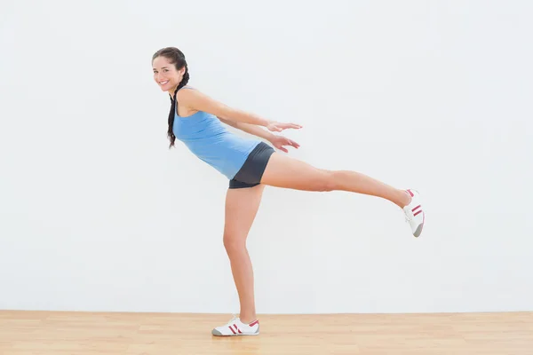 Mujer de pie sobre una pierna en el gimnasio —  Fotos de Stock