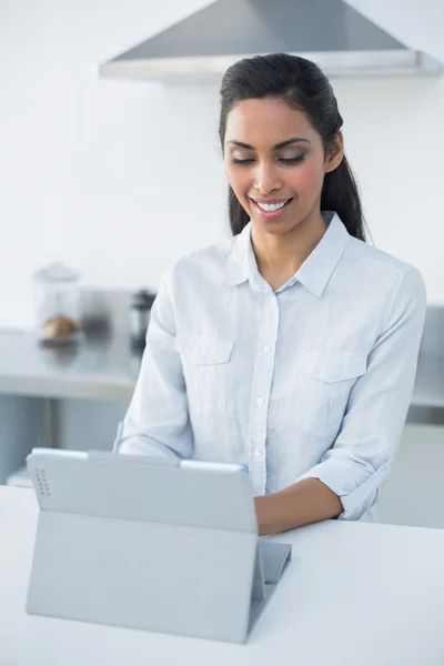 Cute woman using her tablet standing in bright kitchen — Stock Photo, Image